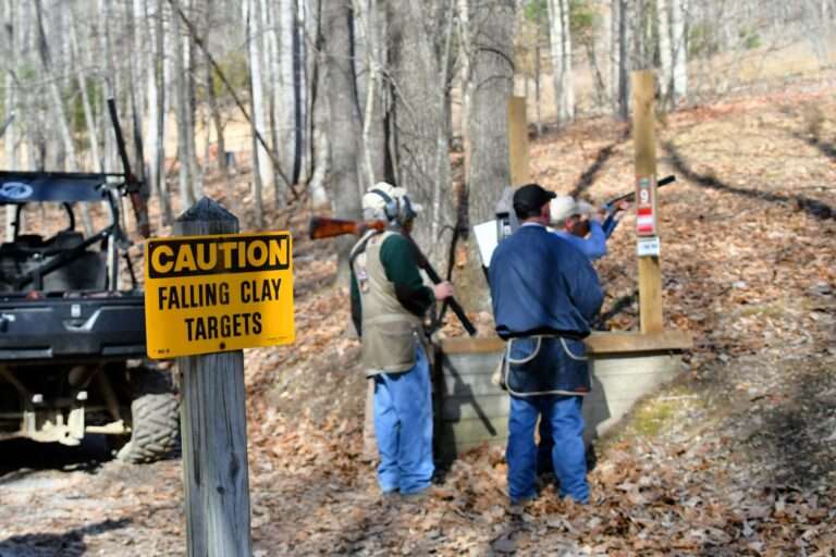 Shooting sporting clay pigeons at a shooting range with shotguns. Caution, falling clay targets sign